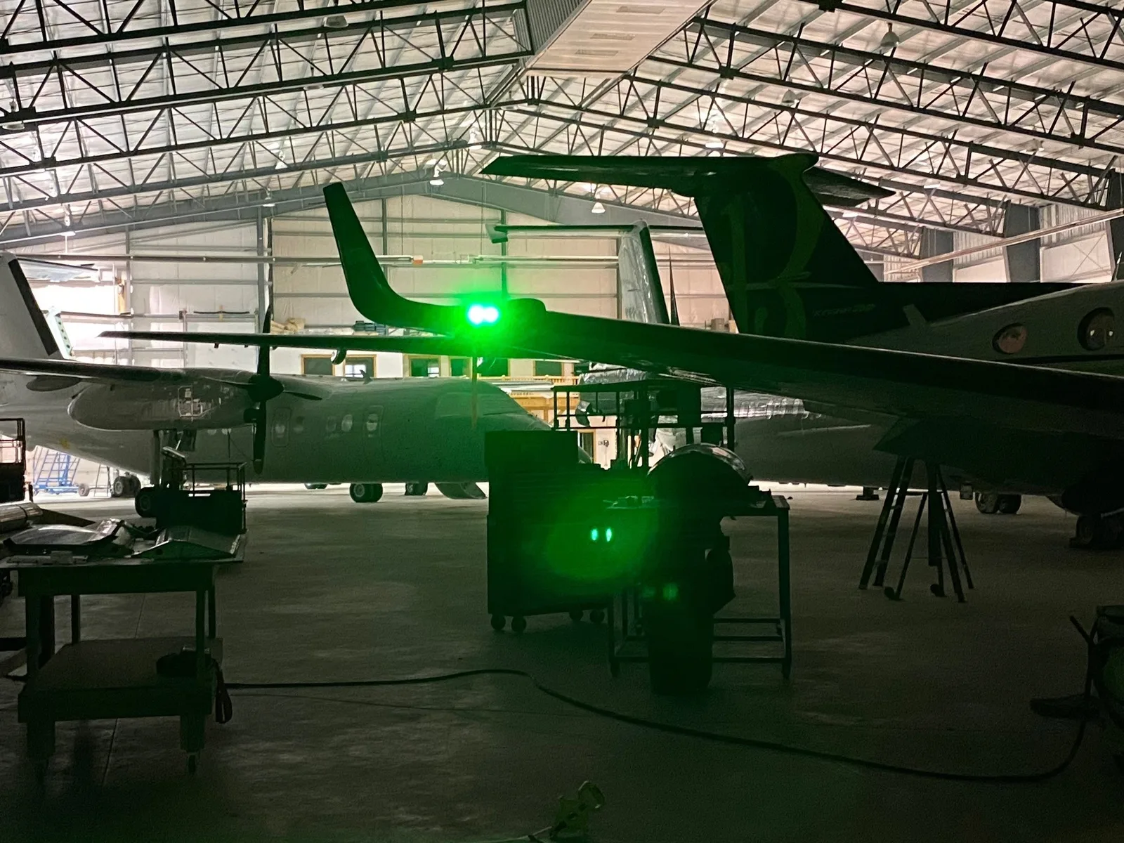 PWI LED wingtip light assembly &mdash; illuminated, installed on aircraft wingtip in hangar