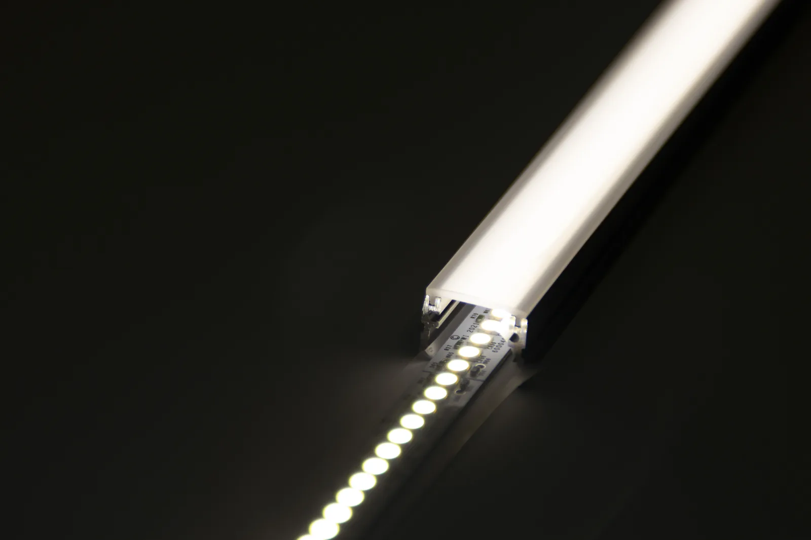PWI LED linear light close-up showing illuminated LED strip, diffuser, and aluminum housing