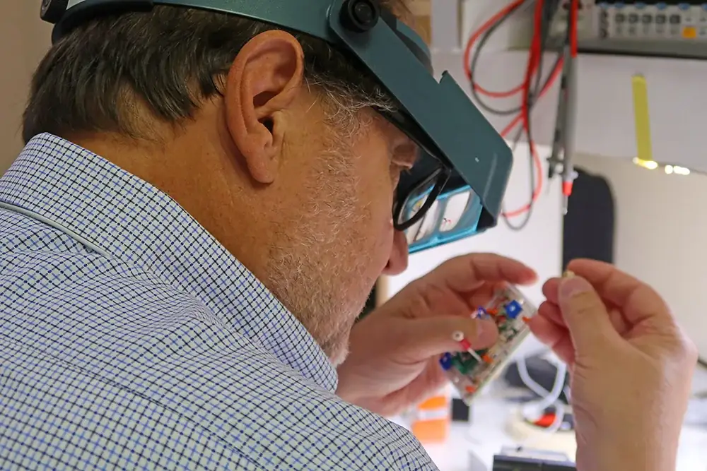 PWI electrical engineer inspecting a circuit assembly under magnification